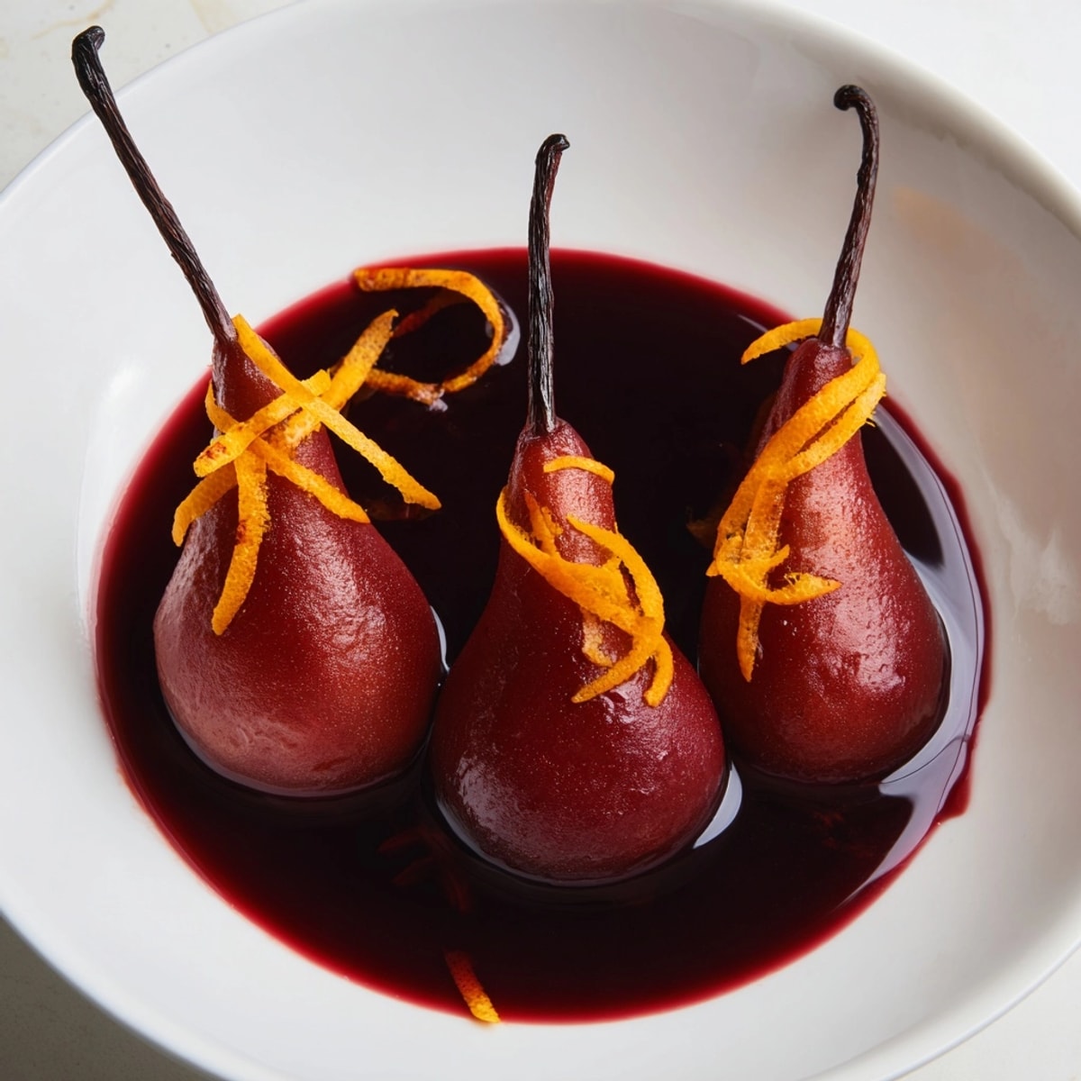 Des poires pochées fondantes dans un sirop de vin rouge épicé, prêtes à être servies.