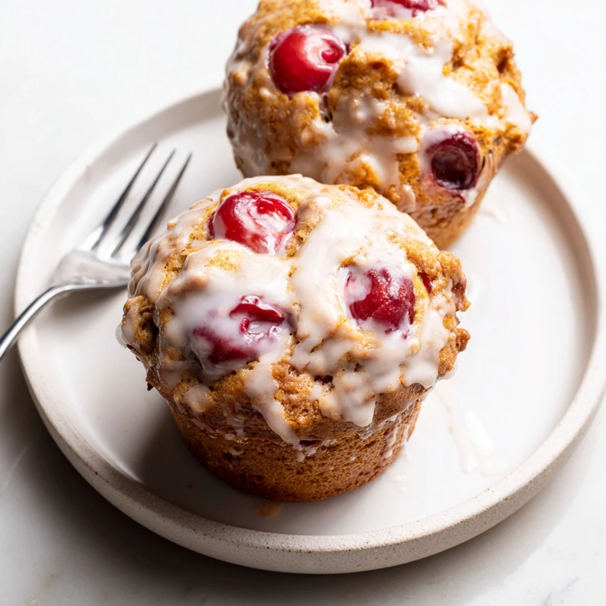 Muffins Cherry Éclair Latte arrosés de glaçage vanille et éclats de cerises juteuses.