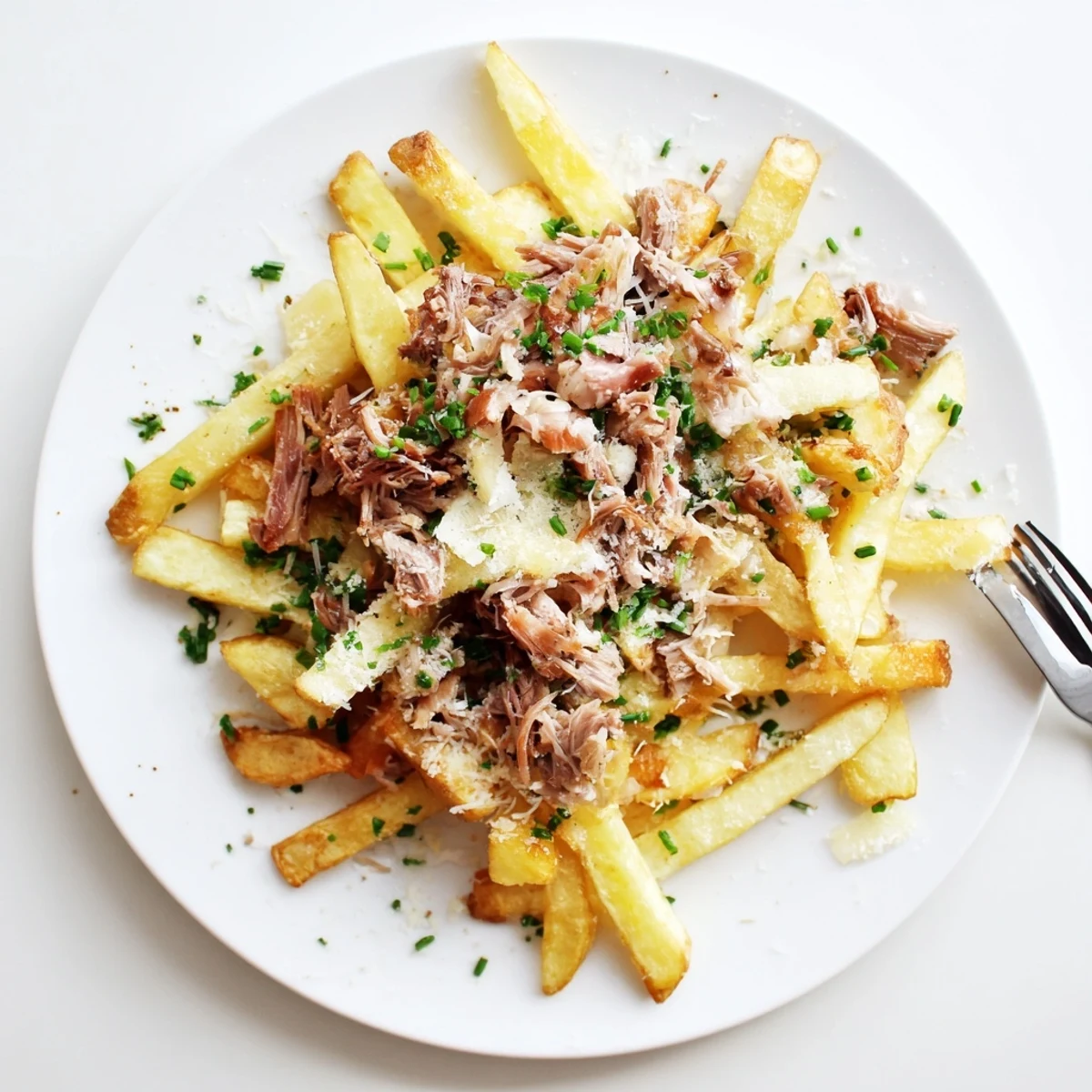 Frites croustillantes dorées garnies de canard confit tendre et herbes fraîches.  