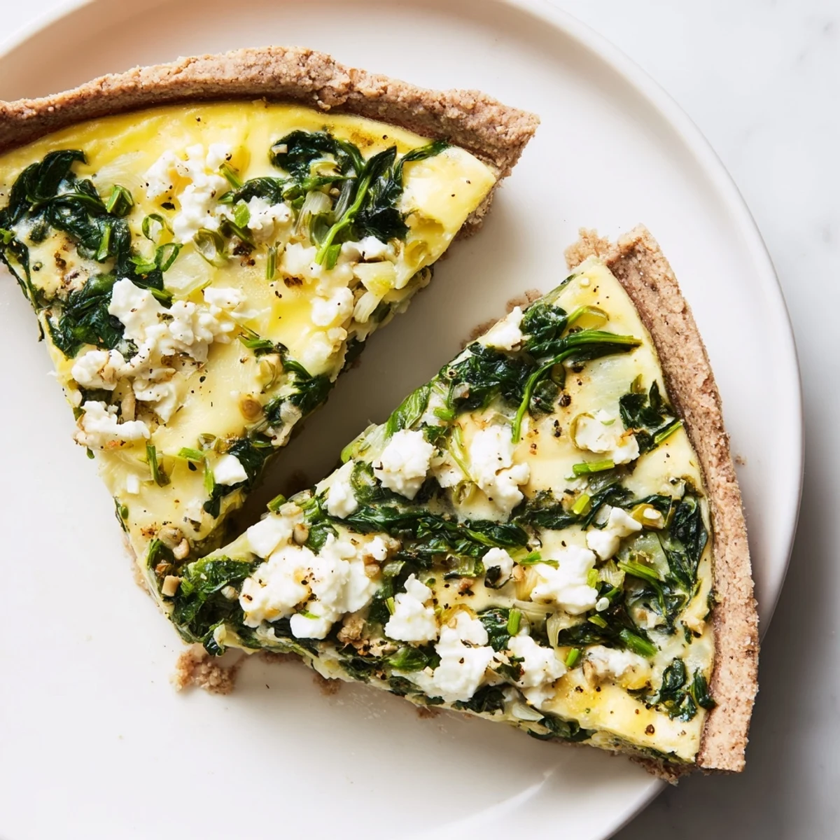 A close-up of a perfectly baked Healthy Spinach & Goat Cheese Quiche, ready to be sliced and served.