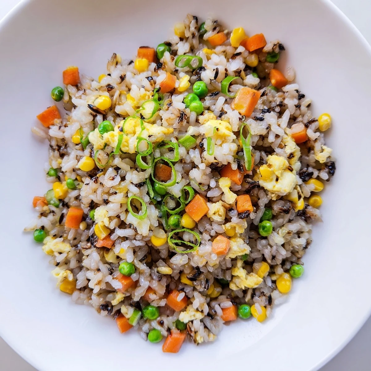 Close-up of golden-brown Black Garlic Fried Rice with vegetables; a savory vegetarian main dish.