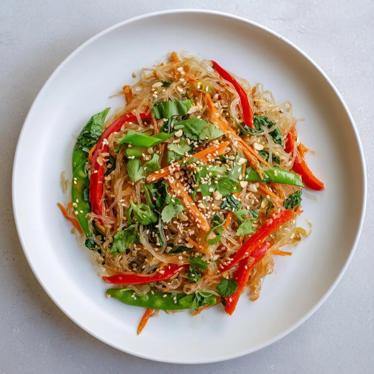 Un plat vibrant de Kelp Noodle Stir-Fry aux légumes colorés et aux graines de sésame, servi avec une lime.