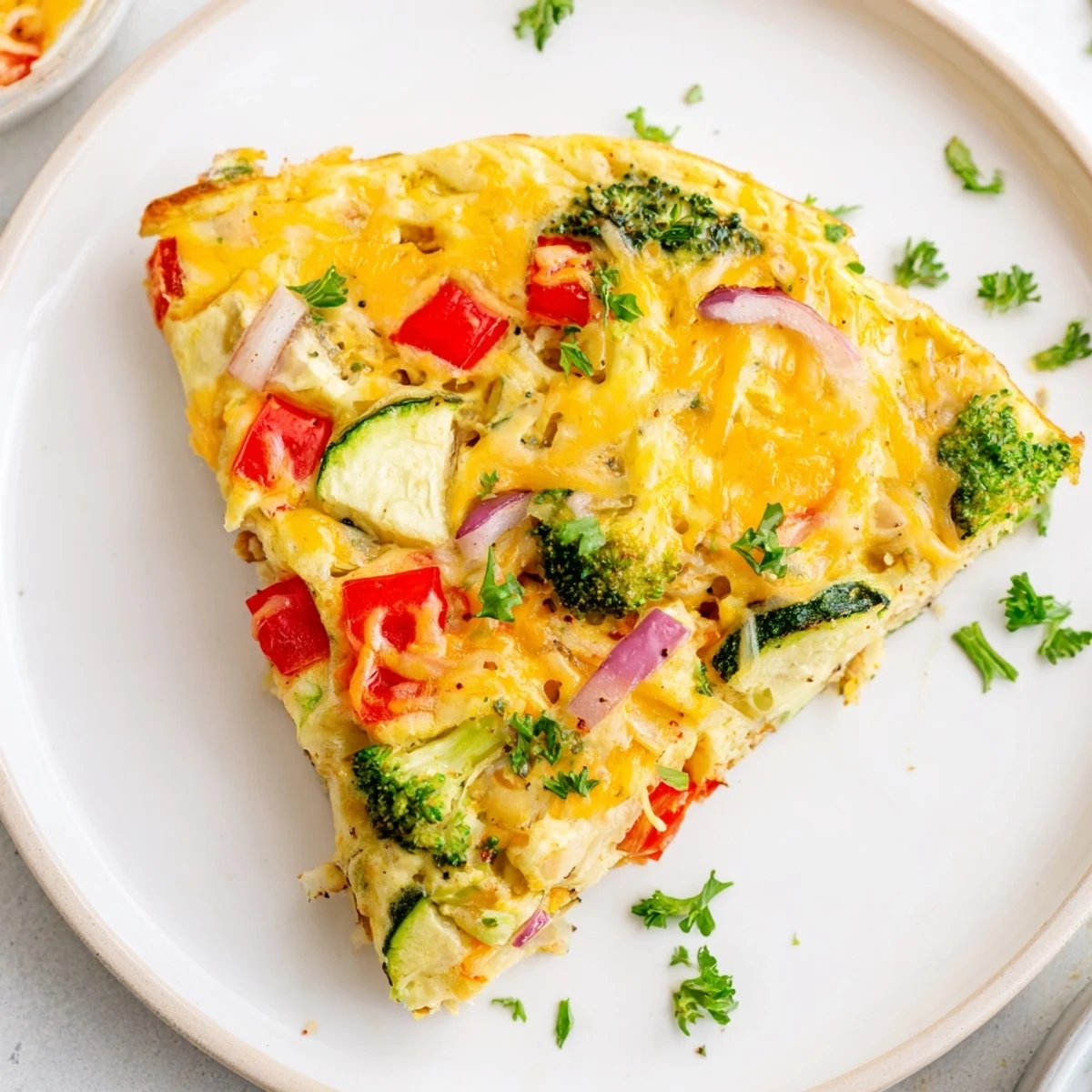 Un vegetable frittata garni de crudités colorées et de fromage fondant, parfait pour un brunch familial savoureux.