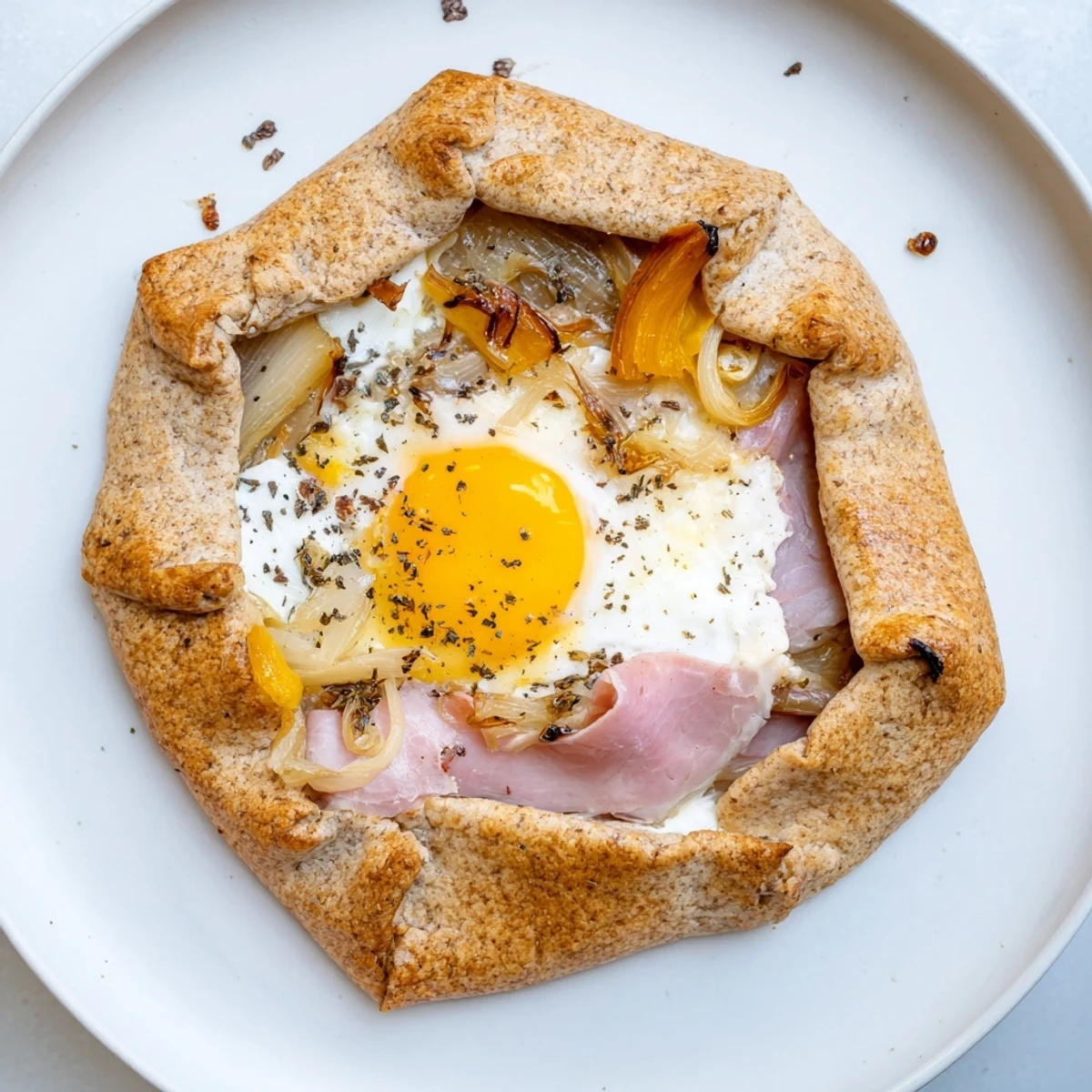 Close-up of a rustic Savory Galette Bretonne, showing layers of buckwheat, cheese, and sweet shallots.