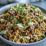 Savoureux Creamy Potsticker Noodle Stir-Fry avec nouilles ramen, chou râpé et morceaux de dinde, saupoudré de graines de sésame et d'oignons verts