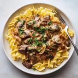 Une assiette de spaghetti bolognaise avec des champignons et des herbes.