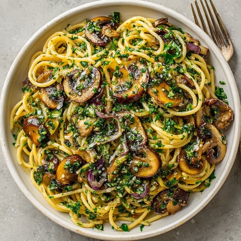 A bowl of pasta with mushrooms and spinach.