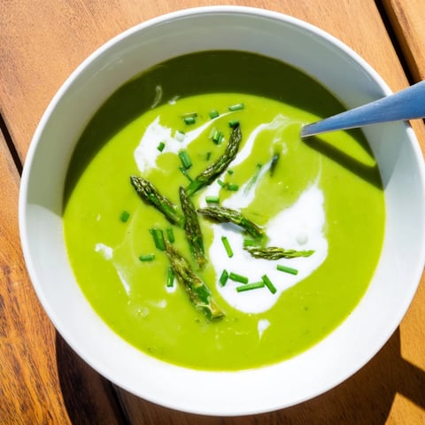 Creamy Asparagus Soup garnished with fresh chives and tender spears in a rustic bowl.