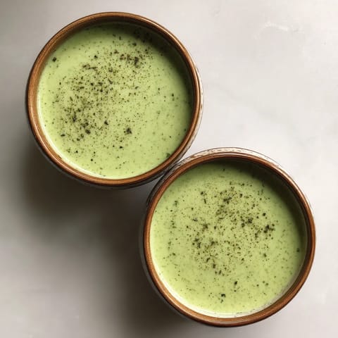 Deux tasses de soupe verte sur un plateau.