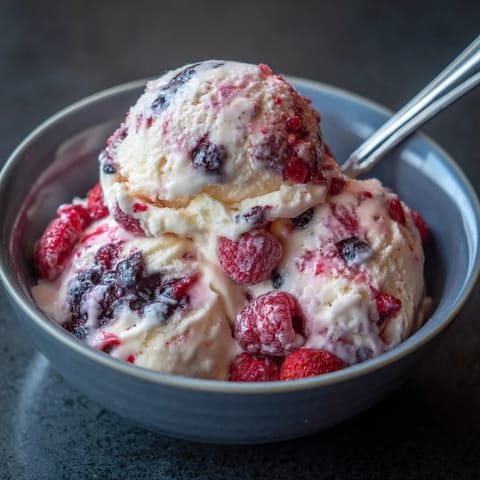 Une tasse de crème glacée avec des morceaux de fraises.