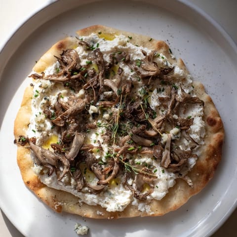 A close-up of a rustic Tarte Flambée showing golden crust, creamy cheese, and flavorful toppings.