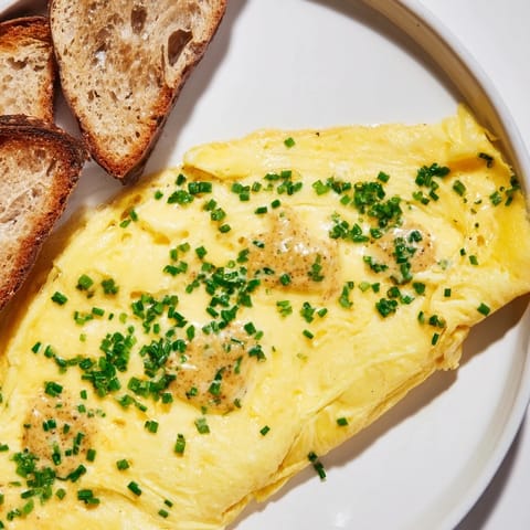 A fluffy, perfectly folded mustard omelette with a side of golden, toasted bread.