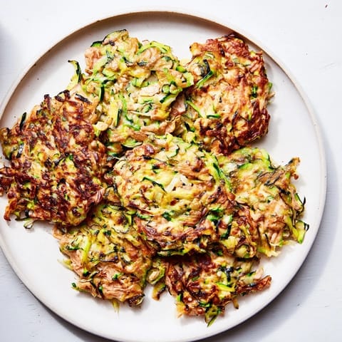 Freshly made High-Protein Chicken Zucchini Fritters, a healthy meal showing fluffy texture and herbs.
