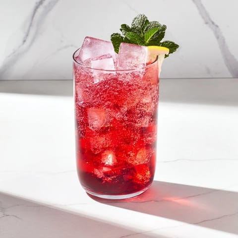 Sleepy Girl Cherry Mocktail in a tall glass, garnished with lemon and mint, perfect for relaxing.