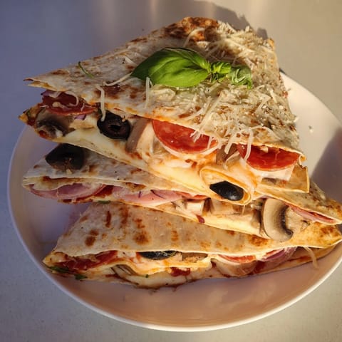 A close-up of a perfectly folded cheesy tortilla pizza wrap, oozing with melted mozzarella and pepperoni.