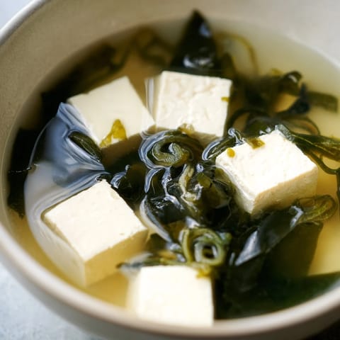 Soupe miso traditionnelle, tofu crémeux et algues marinées, parfaite pour un repas léger et réconfortant.