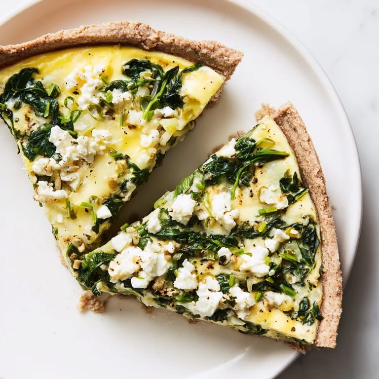 A close-up of a perfectly baked Healthy Spinach & Goat Cheese Quiche, ready to be sliced and served.