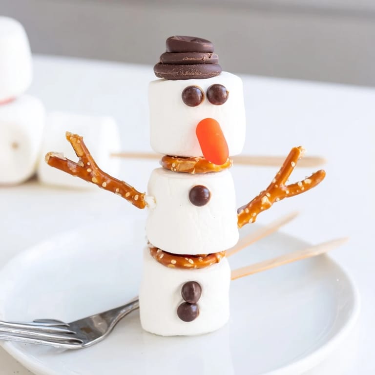 Easy-to-make Marshmallow Snowman Stick Arrangement, perfect for holiday treats and imaginative winter snacks.