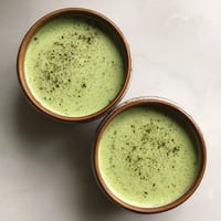 Deux tasses de soupe verte sur un plateau.