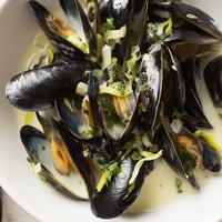 Classic creamy mussels swimming in white wine broth, ready to eat with crusty bread.