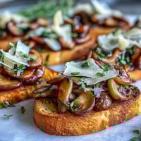 Crostini aux champignons sauvages et à l’ail, toasts dorés nappés de fromage Parmesan et thym frais.