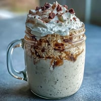 Pot de flocons d'avoine vanille-frappuccino, crémeux et infusé de café, garni de crème fouettée et de copeaux de chocolat.  